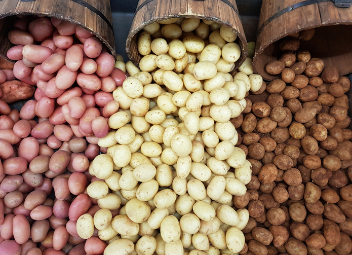 produce-101-potatoes-freshpoint Red, white, and Russet potatoes tumbling out of baskets in a display.
