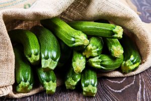 Zucchini squash wrapped in a cloth on a wooden background.
