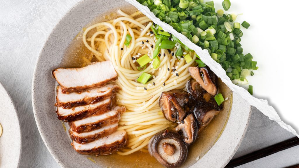 A plated ramen noodle dish with pork slices, shiitake mushrooms, and chopped scallions in a broth, featuring raw scallions. 