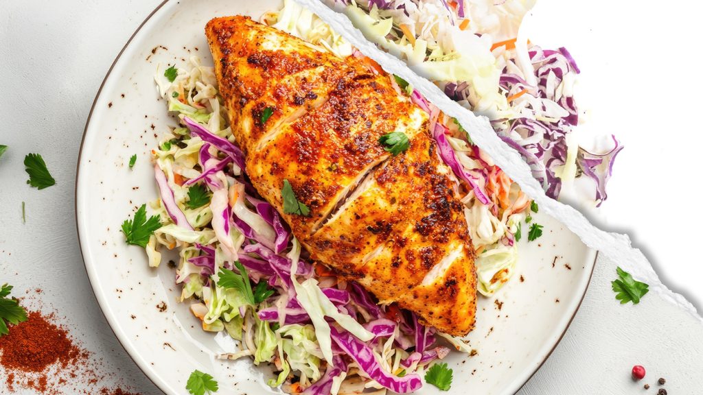 A plated dish of cole slaw and chicken, featuring raw red and green cabbage.