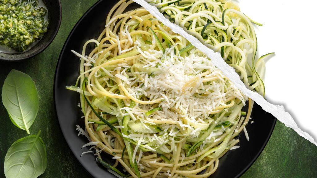 Cooked spaghetti and spiralize zucchini with pesto, featuring raw zucchini spirals. 