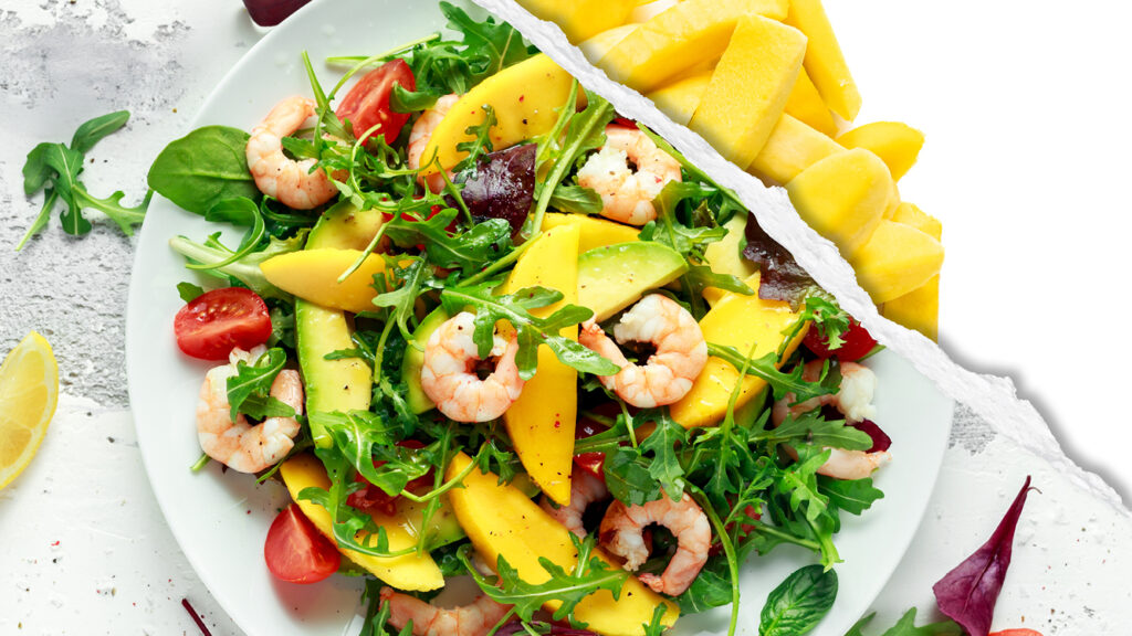 An arugula salad with avocado, shrimp, and sliced mangos. 