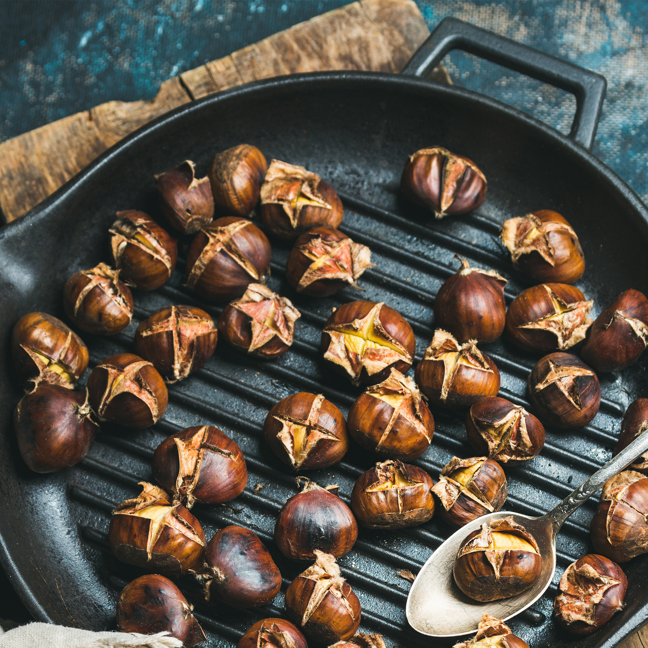 Roasted chestnuts in cast iron pan over dark blue background chestnuts-roasting-freshpoint-produce