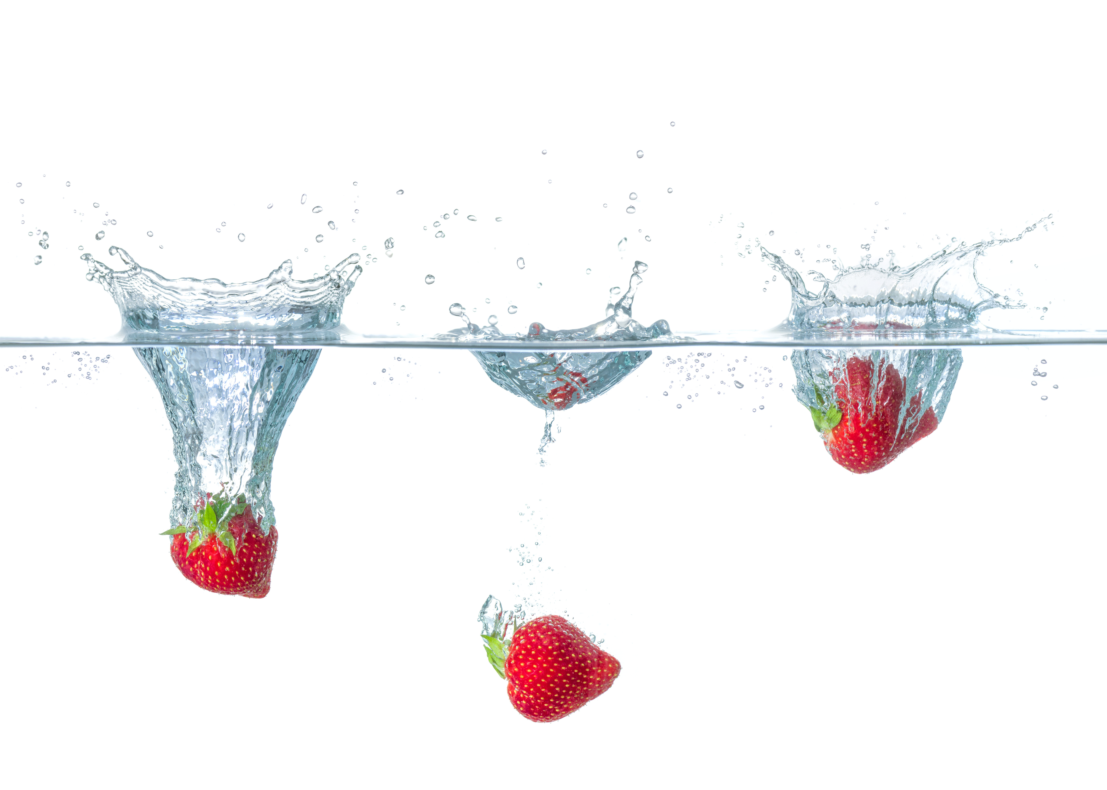 Fresh strawberries falling into water with splashes